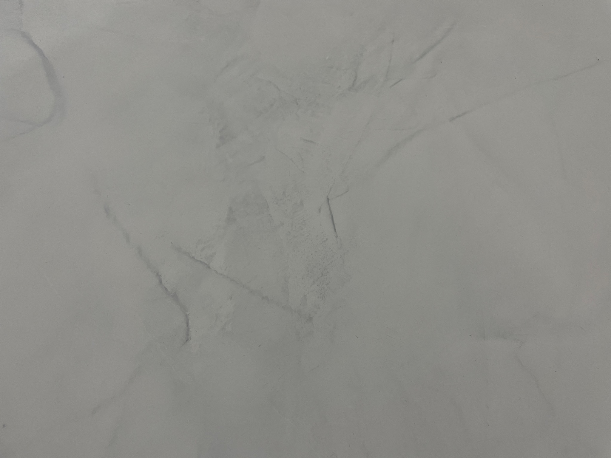 Szara posadzka żywiczna z delikatnym wzorem marmuru, wykonana w technice wylewanej, o matowym wykończeniu.