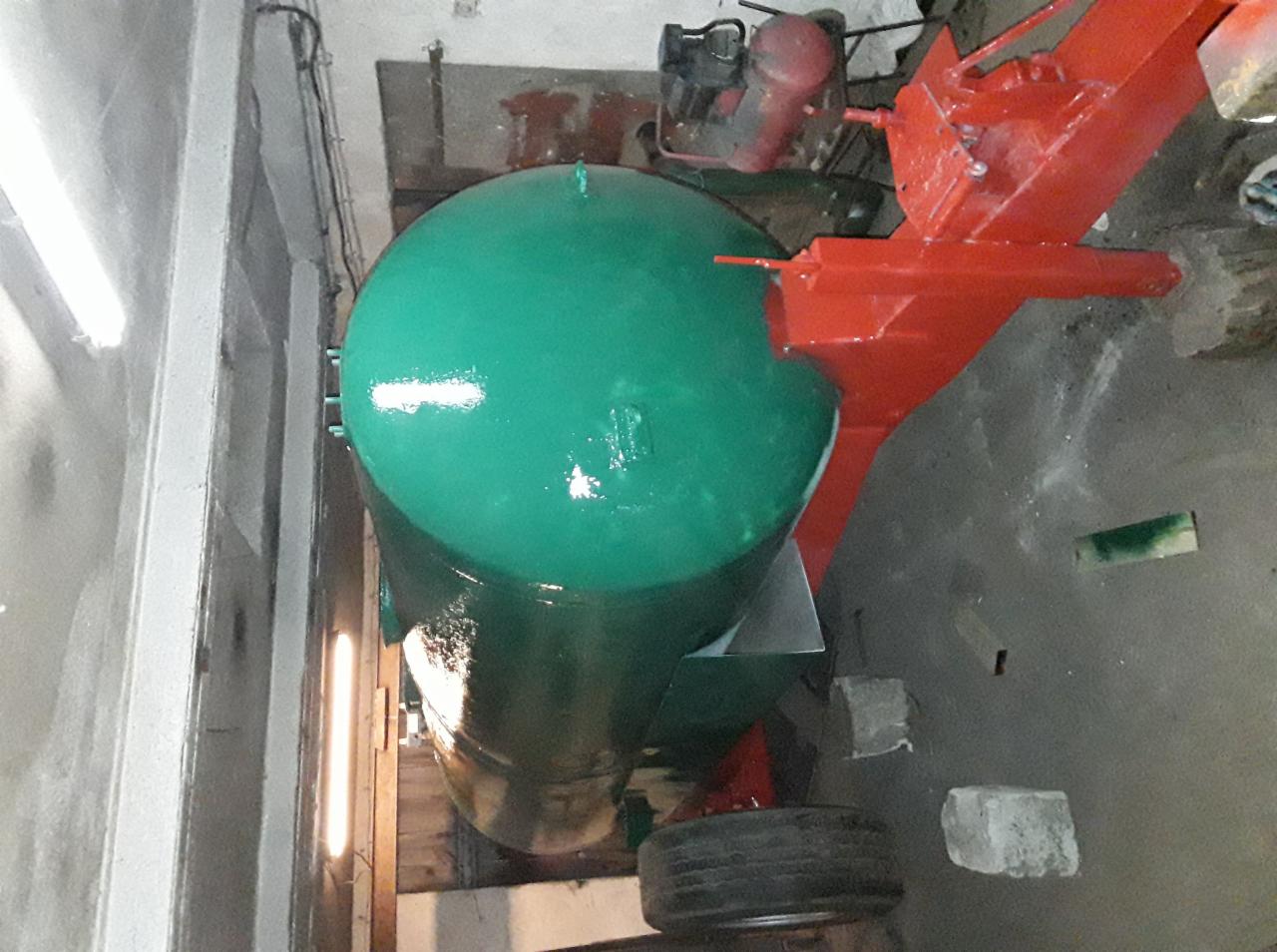 Pomalowany na zielono zbiornik ciśnieniowy z czerwonymi elementami konstrukcyjnymi w hali produkcyjnej.