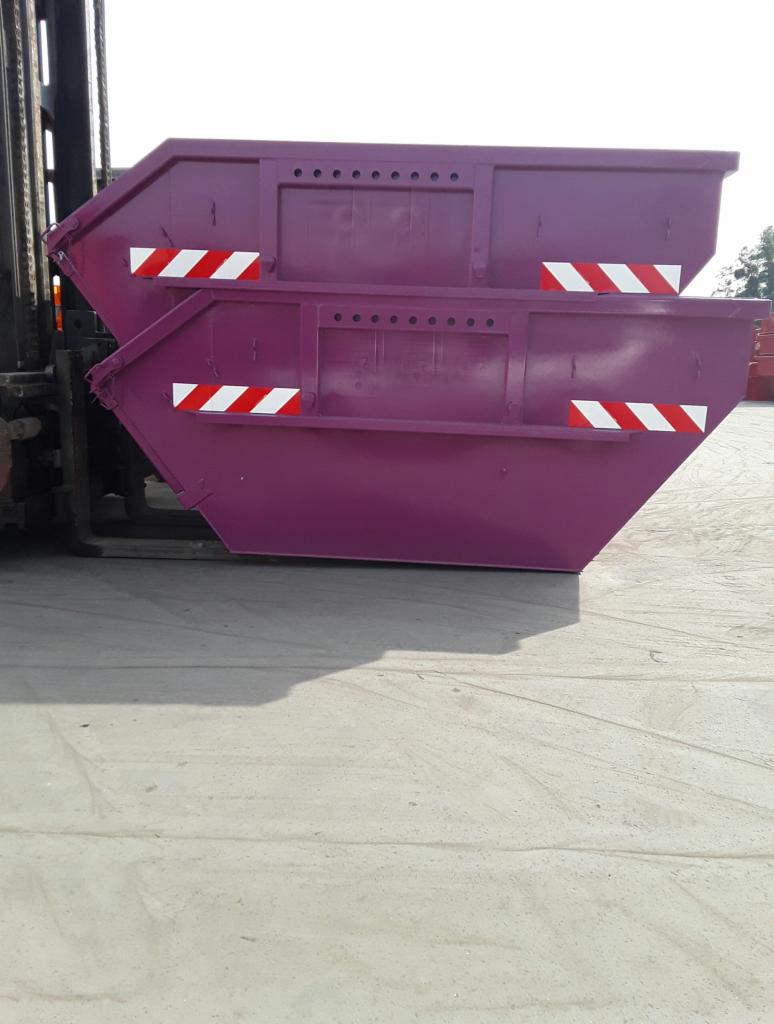 Dwa fioletowe kontenery metalowe z odblaskowymi pasami, jeden na drugim, podnoszone przez wózek widłowy w Gostycynie.