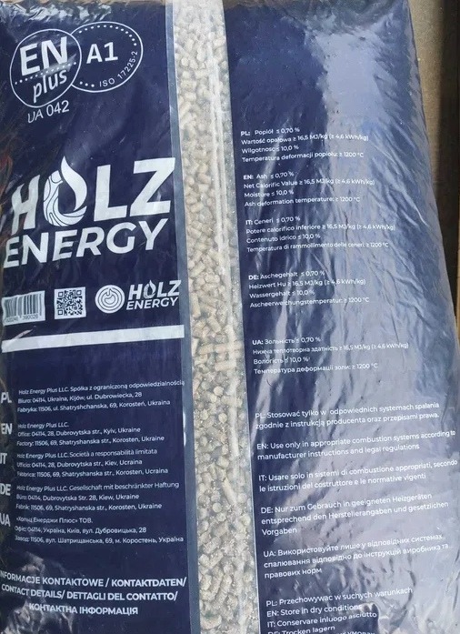 Wypełniony pelletem, niebieski worek z napisem 'HOLZ ENERGY' i certyfikatem ENplus A1, widoczne dane techniczne i kontaktowe producenta w kilku językach.