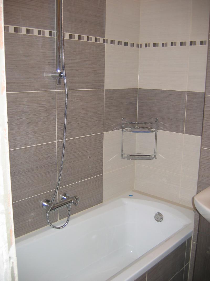 Wykończona łazienka we Wrocławiu z wanną, baterią prysznicową i półką narożną, utrzymana w tonacji beżu i szarości z dekoracyjnym pasem mozaiki.