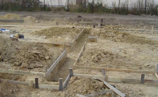 Przygotowanie wykopu i szalunku pod fundamenty budynku na piaszczystym terenie.