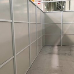 Wnętrze hali z zamontowanymi ściankami działowymi z metalową ramą i wypełnieniem z tworzywa. Widoczne elementy konstrukcyjne hali.