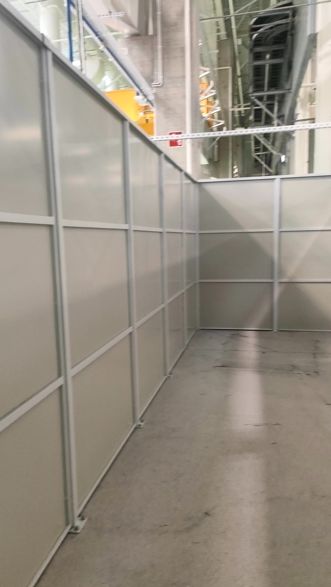 Wnętrze hali z zamontowanymi ściankami działowymi z metalową ramą i wypełnieniem z tworzywa. Widoczne elementy konstrukcyjne hali.