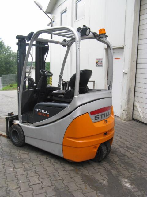 Elektryczny wózek widłowy STILL RX 20-18 z pomarańczowymi akcentami, zaparkowany na zewnątrz magazynu, z widocznym numerem seryjnym na osłonie.