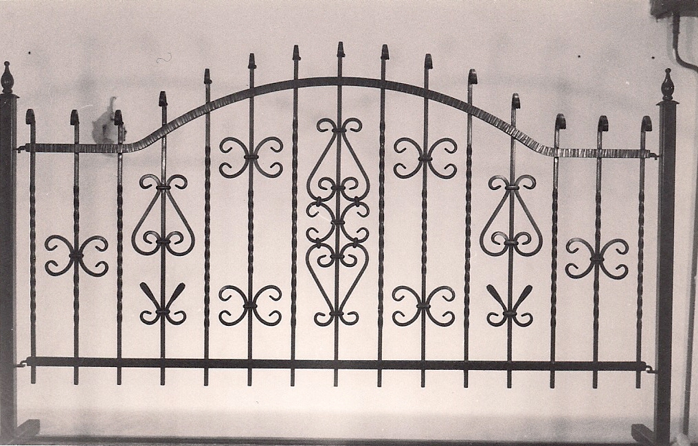 Kuta, metalowa brama z dekoracyjnymi elementami w kształcie serc i spiral, wykończona w stylu retro, z widocznymi śladami ręcznej obróbki metalu.