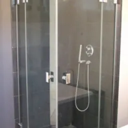 Szklana kabina prysznicowa z czarnymi płytkami i siedziskiem w Toruniu, widok z zewnątrz, chromowane okucia.