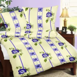 Komplet pościeli z motywem niebieskich kwiatów i pasków, uszyty w Bielawie, leży na łóżku z drewnianą ramą.