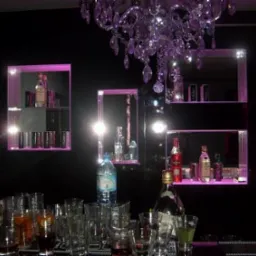 Lustrzane półki z fioletowym podświetleniem, na których stoją butelki z alkoholem, nad nimi wisi kryształowy żyrandol, a na blacie stoją szklanki i butelki.