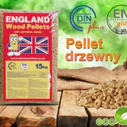 Worek pelletu drzewnego England Wood Pellets 15kg na drewnianym stole, obok rozsypany pellet, w tle worek jutowy. Widoczne certyfikaty DIN plus i EN plus.