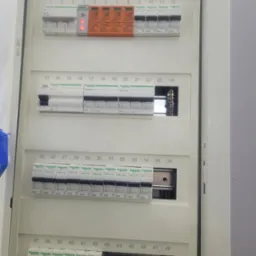 Otwarta skrzynka elektryczna z widocznymi zabezpieczeniami przepięciowymi, wyłącznikami różnicowoprądowymi i nadprądowymi marki Schneider Electric i Noark, oznaczona numerami od 1 do 48.