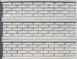 Szary, betonowy płot z imitacją cegieł, podzielony na trzy poziome panele, oświetlony równomiernym światłem.