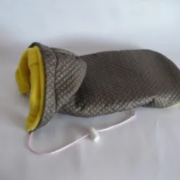 Ocieplacz na dłoń z pikowanej tkaniny w odcieniach szarości, z żółtą podszewką i różowym sznurkiem ze stoperem, leżący na białym tle.