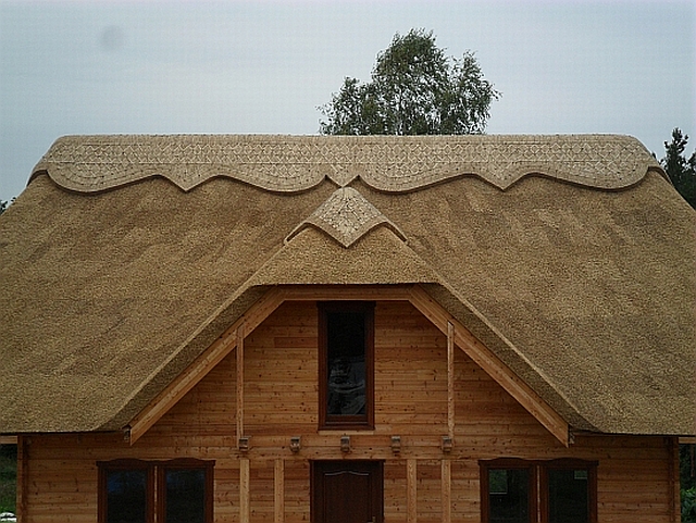 Drewniany dom z dachem krytym strzechą z trzciny z dekoracyjnym wykończeniem krawędzi dachu.