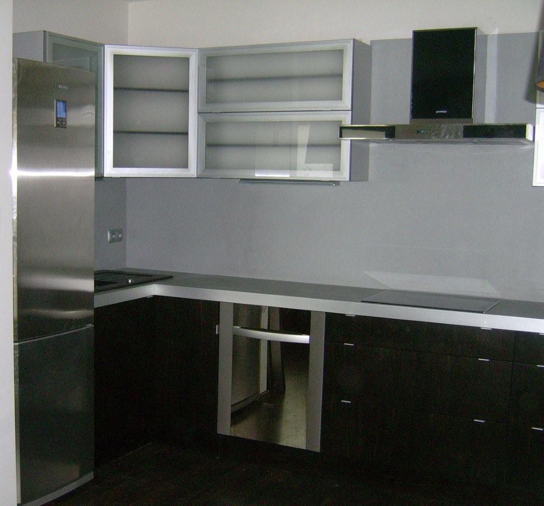 Nowoczesna kuchnia z ciemnymi szafkami dolnymi, jasnymi górnymi i srebrnym blatem, uzupełniona o srebrną lodówkę i okap.