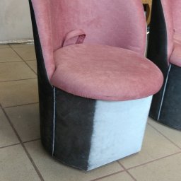 Mbaldi - Różowe krzesło tapicerowane z czarno-białym dołem, widoczne drugie krzesło w tle, na podłodze z płytek.