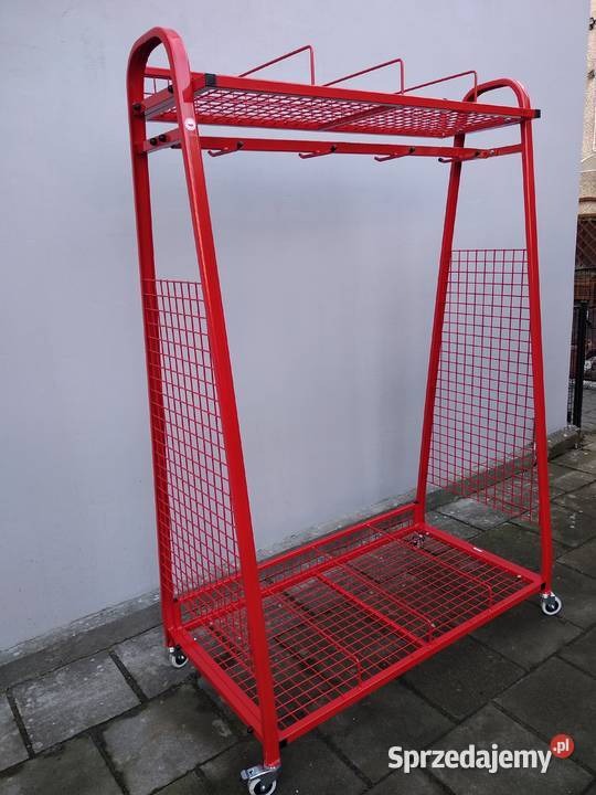 Czerwony, metalowy wózek warsztatowy z siatkowymi ściankami i półkami, na kółkach, ustawiony na zewnątrz przy szarej ścianie.