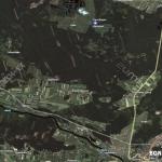 Zdjęcie lotnicze działki zalesionej w pobliżu zabudowań, widok z góry na teren z wyraźnymi granicami, otoczony drzewami i drogami.