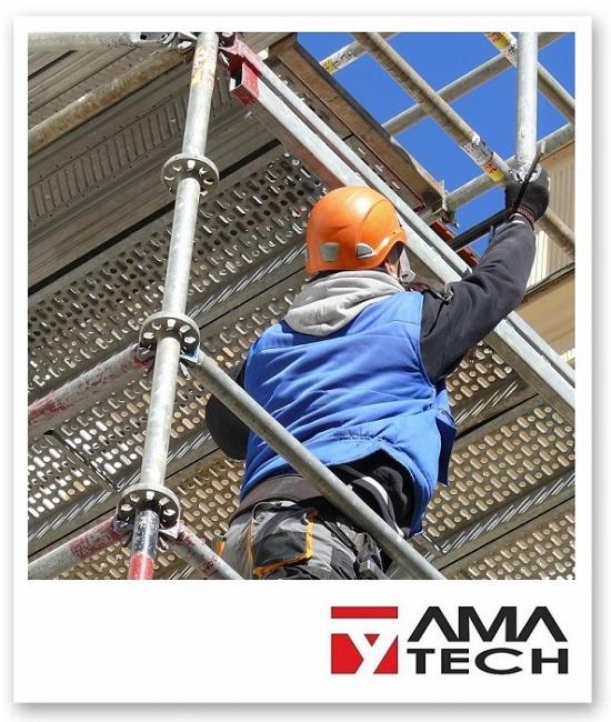 Pracownik w pomarańczowym kasku i niebieskiej kamizelce montuje metalowe rusztowanie na tle błękitnego nieba, widoczne logo firmy AMA TECH.