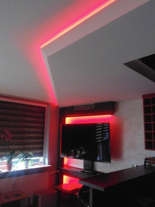 Pokój z podświetlanym sufitem i ścianami na czerwono. Nowoczesne wykończenie wnętrza z telewizorem i oknem z żaluzjami.