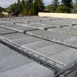 Szare, betonowe pustaki stropowe ułożone na konstrukcji z prętów zbrojeniowych, widok z góry na budowie.