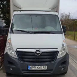 Biały samochód dostawczy Opel Master z zabudową kontenerową, zaparkowany na ulicy, widok z przodu na tablicę rejestracyjną WPR 6415R.