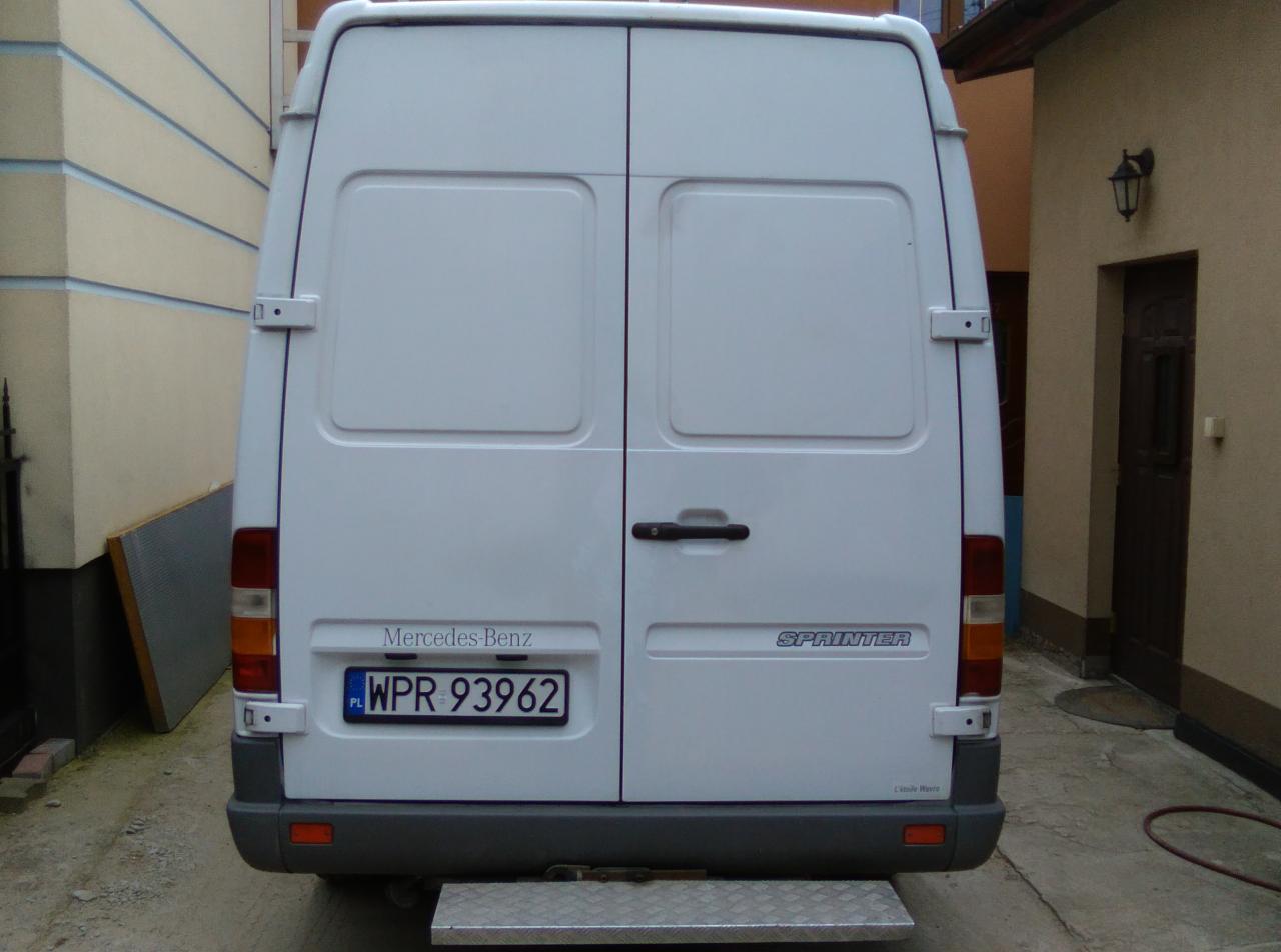 Tył białego samochodu dostawczego Mercedes-Benz Sprinter z polską tablicą rejestracyjną WPR 93962, widok z bliska na drzwi i stopień.