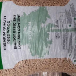 Worek z przezroczystego tworzywa wypełniony pelletem drzewnym, na worku zielono-białe nadruki informujące o parametrach produktu: 'Wood Pellets', 'Premium Quality Pine Wood', 'Energy Efficient'...