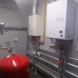 Nowoczesna kotłownia z kotłem gazowym i zasobnikiem ciepłej wody, rury w izolacji, Bukowiec. Widoczne elementy instalacji grzewczej.