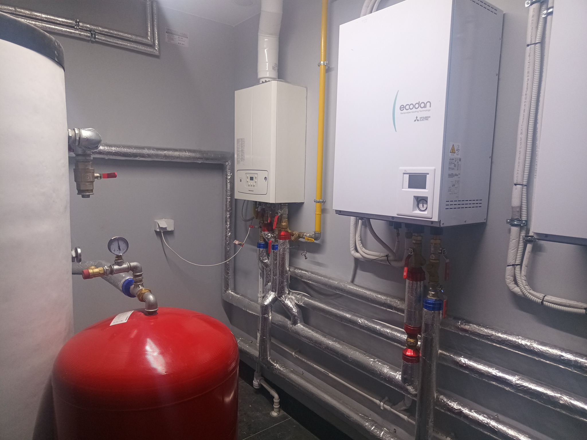 Nowoczesna kotłownia z kotłem gazowym i zasobnikiem ciepłej wody, rury w izolacji, Bukowiec. Widoczne elementy instalacji grzewczej.