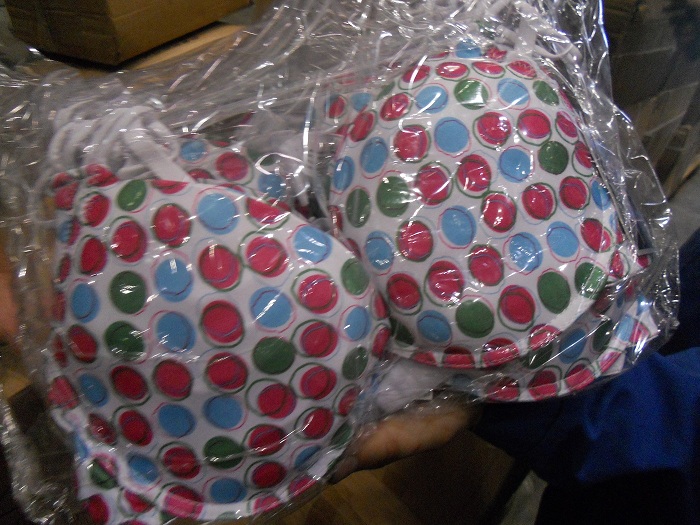 Dwa biustonosze push-up w przezroczystym opakowaniu foliowym, z białym tłem w kolorowe kropki (czerwone, niebieskie, zielone) obwiedzione czarną linią.