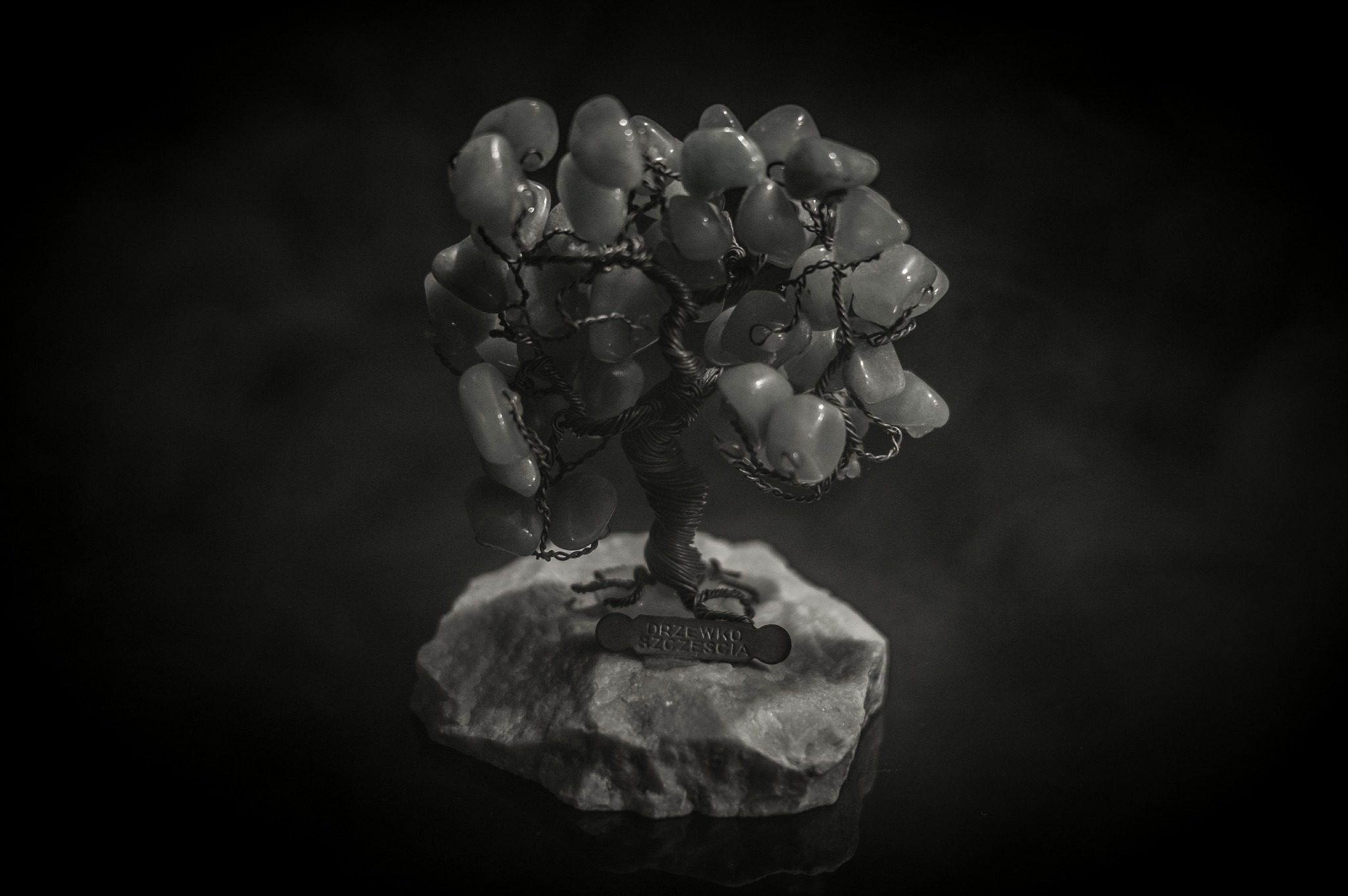 Ręcznie robione drzewko szczęścia z kamieni, umieszczone na surowej skale, w odcieniach szarości.