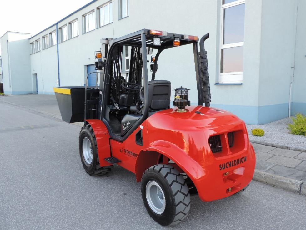 Czerwony wózek widłowy ML35 marki Suchedniów, z czarnym przeciwwagą, stoi na zewnątrz budynku. Widoczne opony z bieżnikiem i metalowa konstrukcja kabiny.