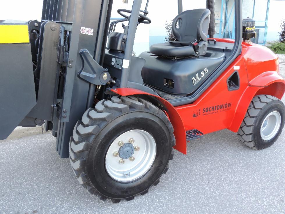 Czerwony wózek widłowy M.35 Suchedniów z czarnym siedziskiem i oponami terenowymi, widok z boku na zewnątrz, z widocznymi detalami konstrukcyjnymi.