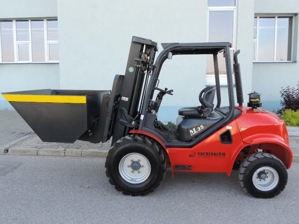Czerwony wózek widłowy M.35 Suchedniów z czarnym pojemnikiem na widłach, zaparkowany na zewnątrz budynku z oknami.