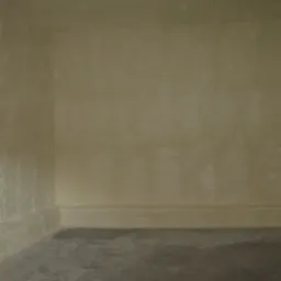 Wnętrze z otynkowanymi ścianami w odcieniach beżu i szarości, widoczny narożnik i fragment podłogi. Teksturowana powierzchnia ścian.