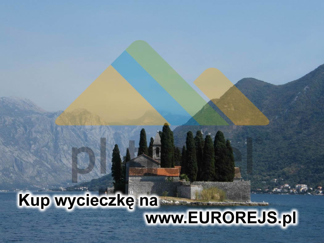 Malownicza wyspa z kamiennym kościołem i cyprysami na tle gór i błękitnego morza, widok z oddali.