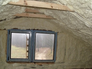 Poddasze z oknem, ocieplone pianą PUR, widoczne drewniane elementy konstrukcji dachu.